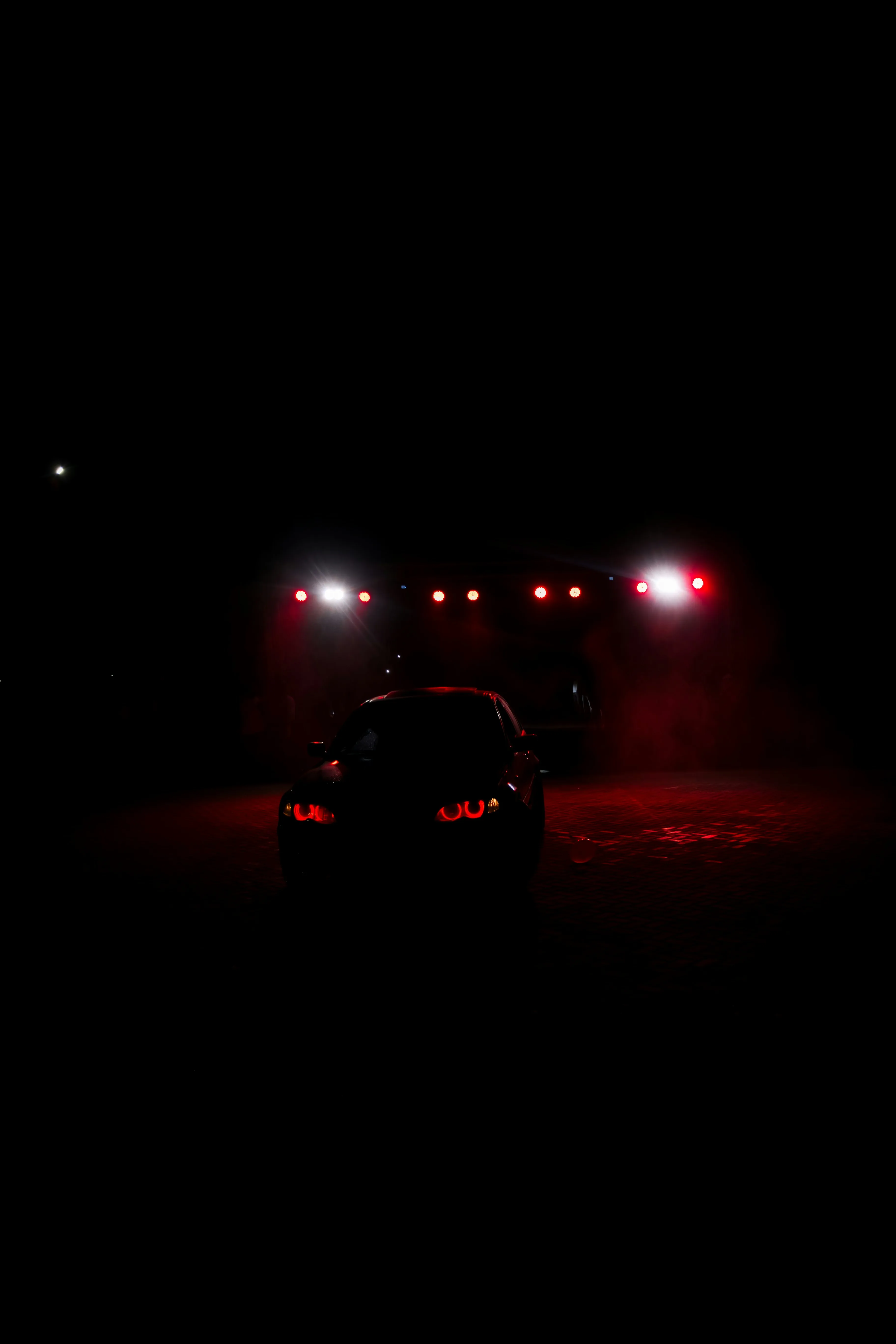 Silhouette of a car with glowing red lights at night