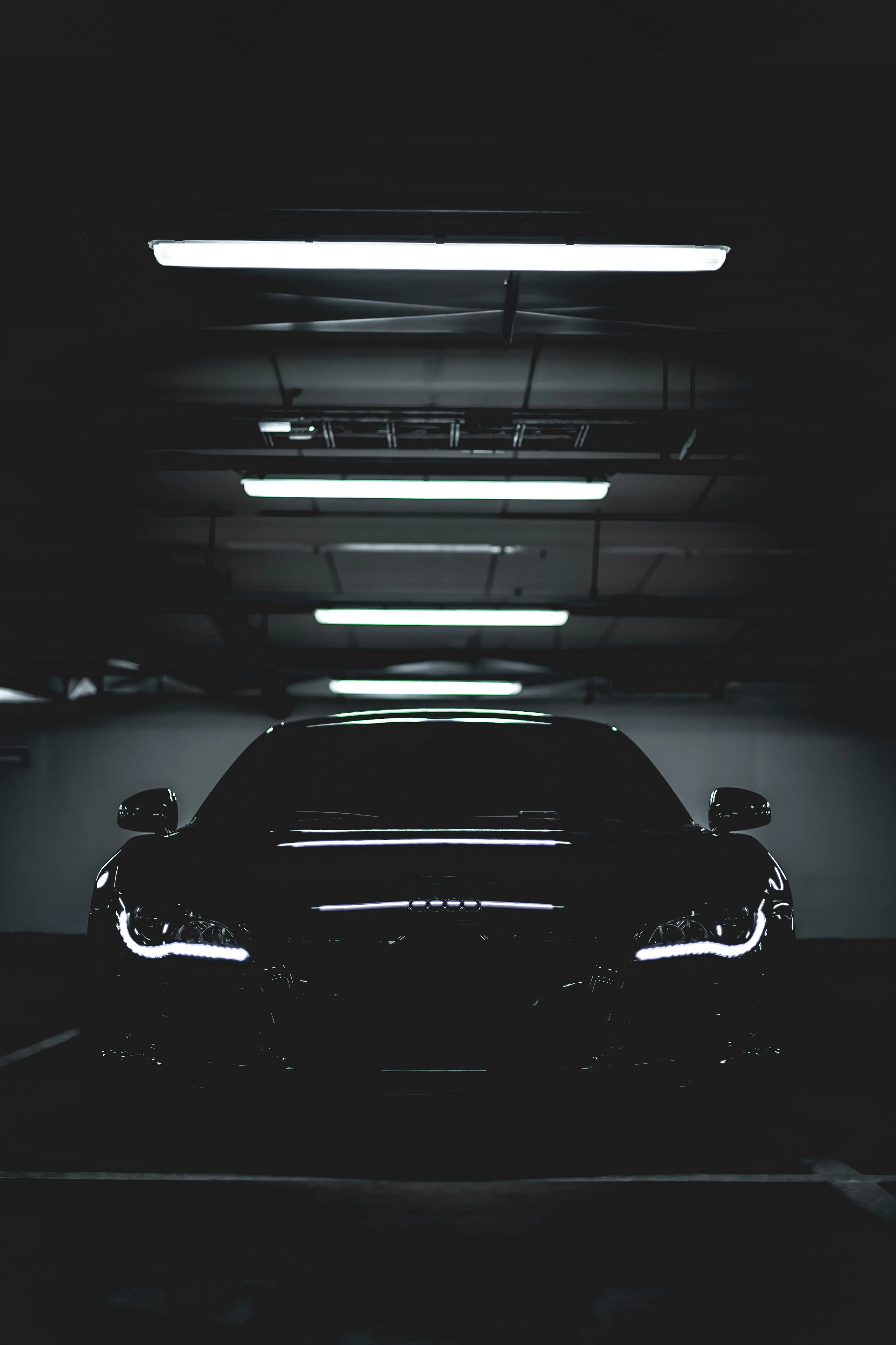 Front view, black car in a dark garage