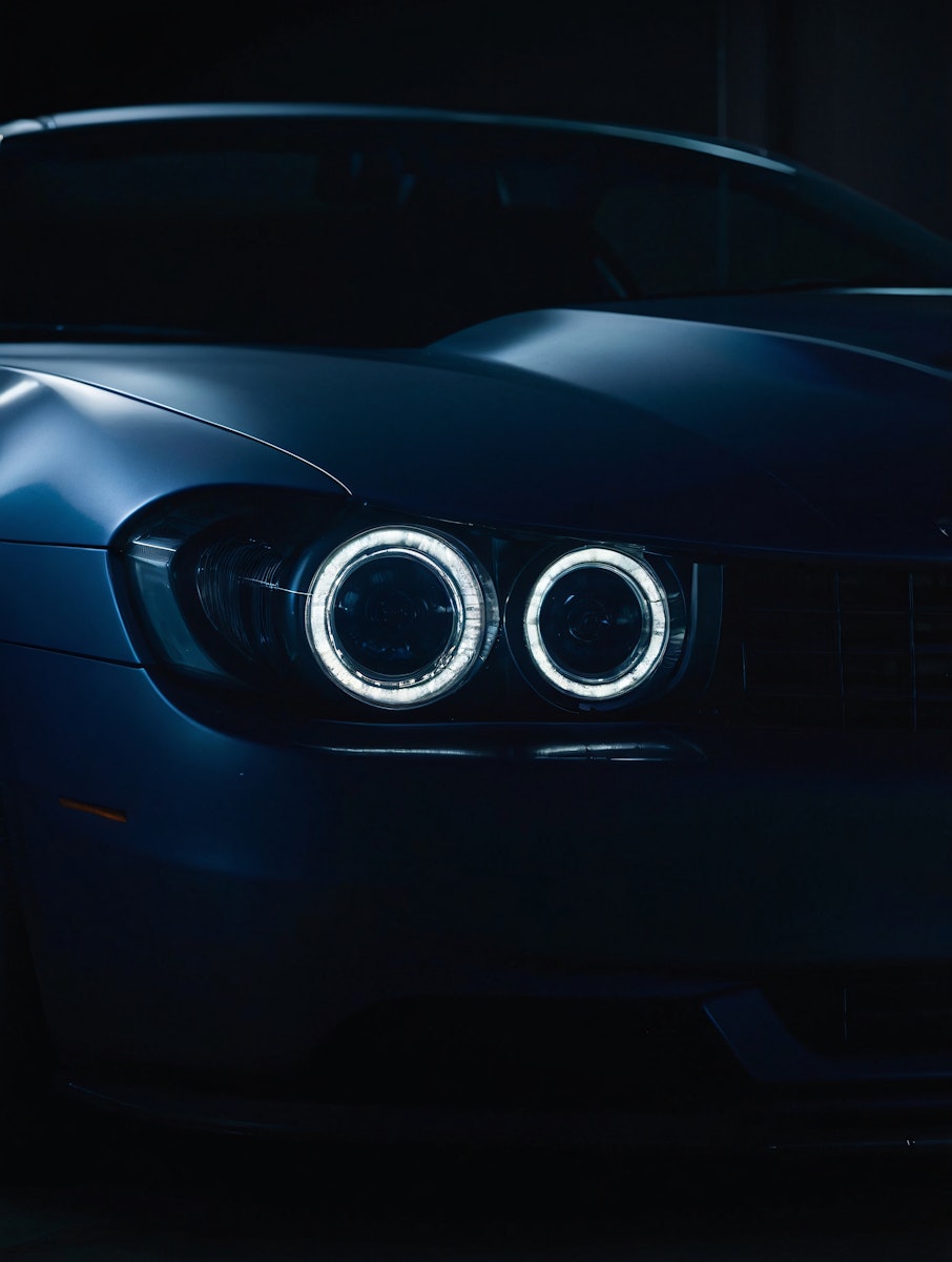 Close-up of glowing circular car headlights at night